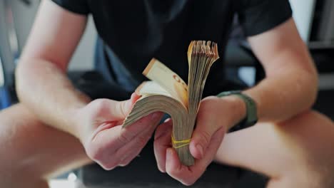 man flips through thick stack of euro bills in daylight – wealth display moment