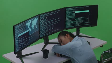 vista lateral de una desarrolladora asiática cansada durmiendo mientras escribe código con múltiples pantallas de computadora en el estudio de pantalla verde