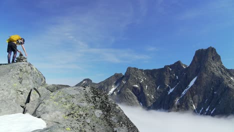 static shot of a mountaineer making the last move to the peak of an mountain above the cloud