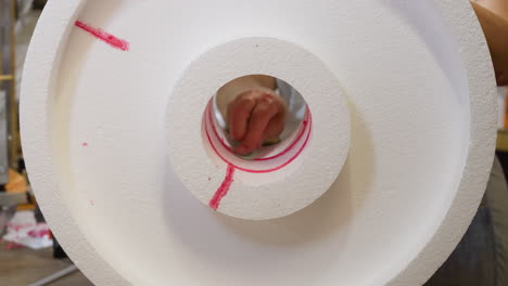 close-up of a polystyrene foam roll with red marking, hand in motion