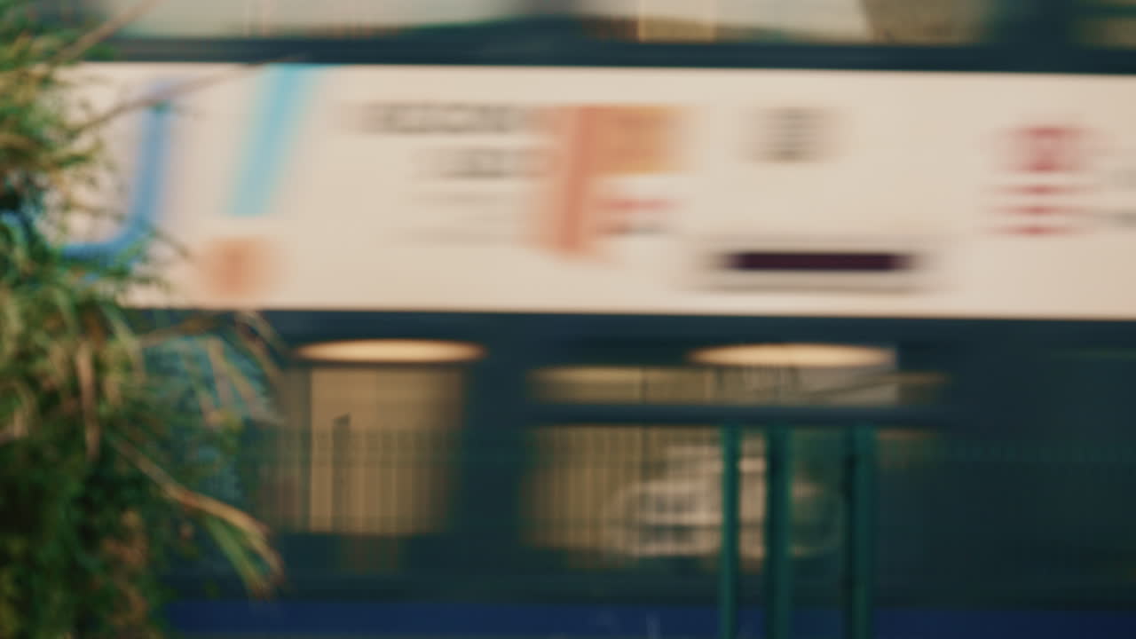 Scatto astratto di un treno ad alta velocità che passa dietro una recinzione metallica, creando un effetto mosso e una linea geometrica