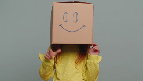 preteen child kid frustrated after quarrel wearing cardboard box with smiling face to change mood