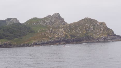 A-Boat-Passing-by-a-Moody,-Mysterious-and-Rocky-Island-in-Islas-Cies-in-the-Atlantic-Ocean