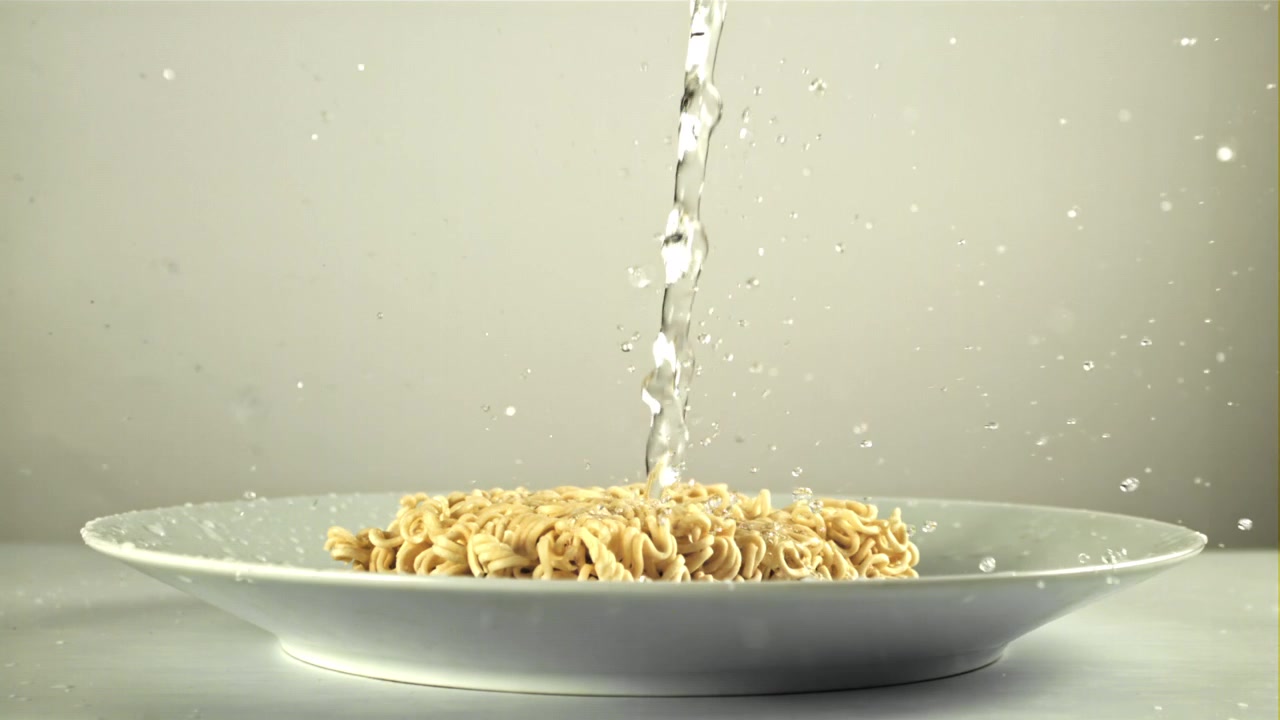 Acqua che si versa al rallentatore su noodles istantanei secchi