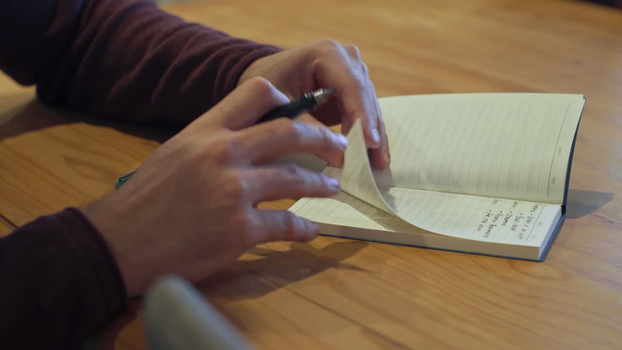 Side shot of man opening notebook to write in