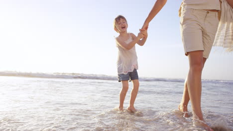 Familia-Feliz-Jugando-En-Las-Olas-En-La-Playa-Al-Atardecer-De-Vacaciones