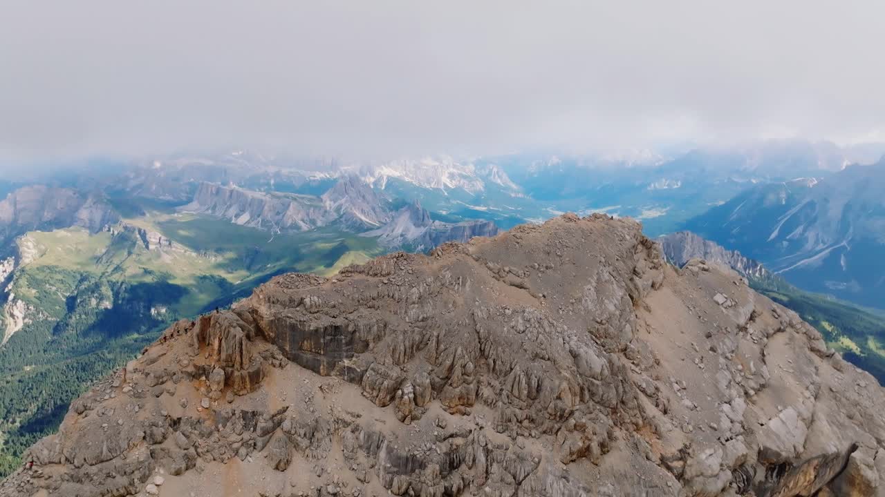 toma aérea hacia atrás que muestra la montaña rocosa y el valle verde en segundo plano durante el día nublado en italia