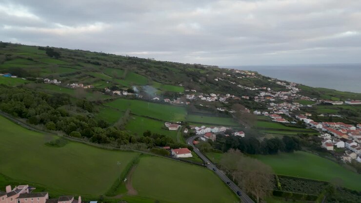 Veduta aerea di un villaggio e di una campagna lussureggiante di fronte all'oceano