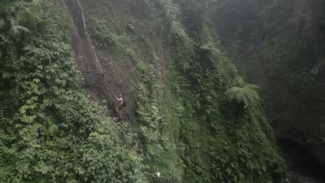 el turista masculino sube una escalera empinada por el estrecho cañón de la selva de java