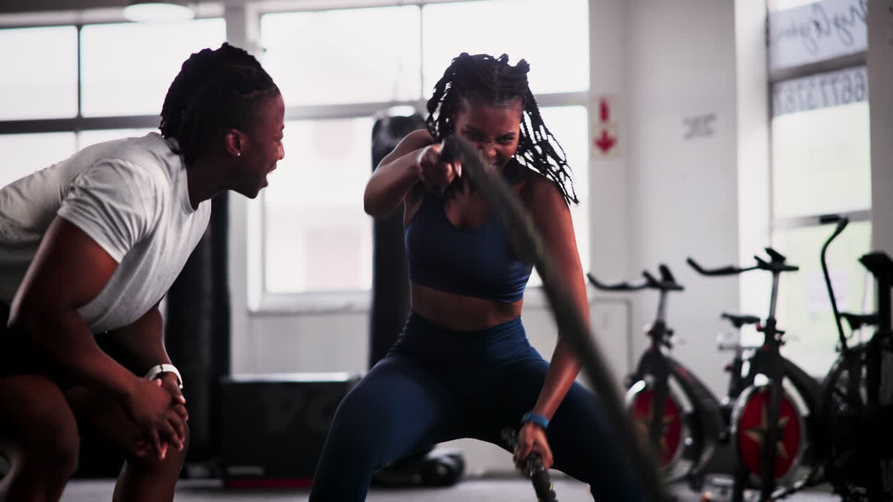 Two people workout with a battle rope in the gym