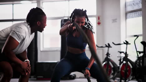two people workout with a battle rope in the gym