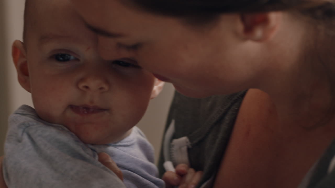 집 에서 아기 를 안고 있는 젊은 어머니 는 신생아 를 진정 시키며 어머니 는 아기 를 부드럽게 진정 시키며 양육 하는 어머니 를 즐긴다