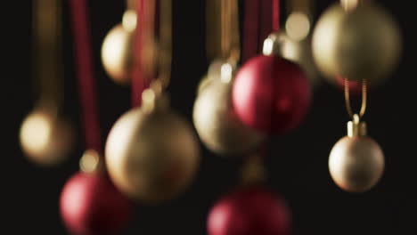 video of gold and red christmas baubles decorations with copy space on black background