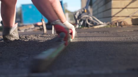 concrete worker leveling fresh wet surface with wooden float