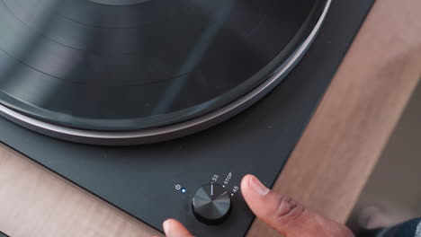 hand of man activates switch on turntable. african american music lover entertains visitors immersed in favorite tunes through turntable. music background