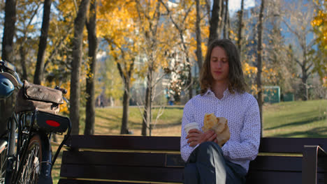 front view of young caucasian man having coffee in the park 4k