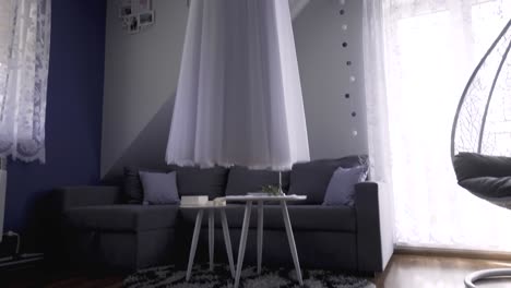 vestido de novia largo colgado en una habitación diminuta con zapatos en el suelo