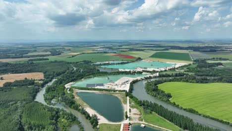 Die-Luftdrohne-Steigt-Auf-Und-Enthüllt-Den-Kleinen-Fluss-Donau,-Die-Smaragdgrünen-Seen-Und-Die-Weiten-Felder-Darunter