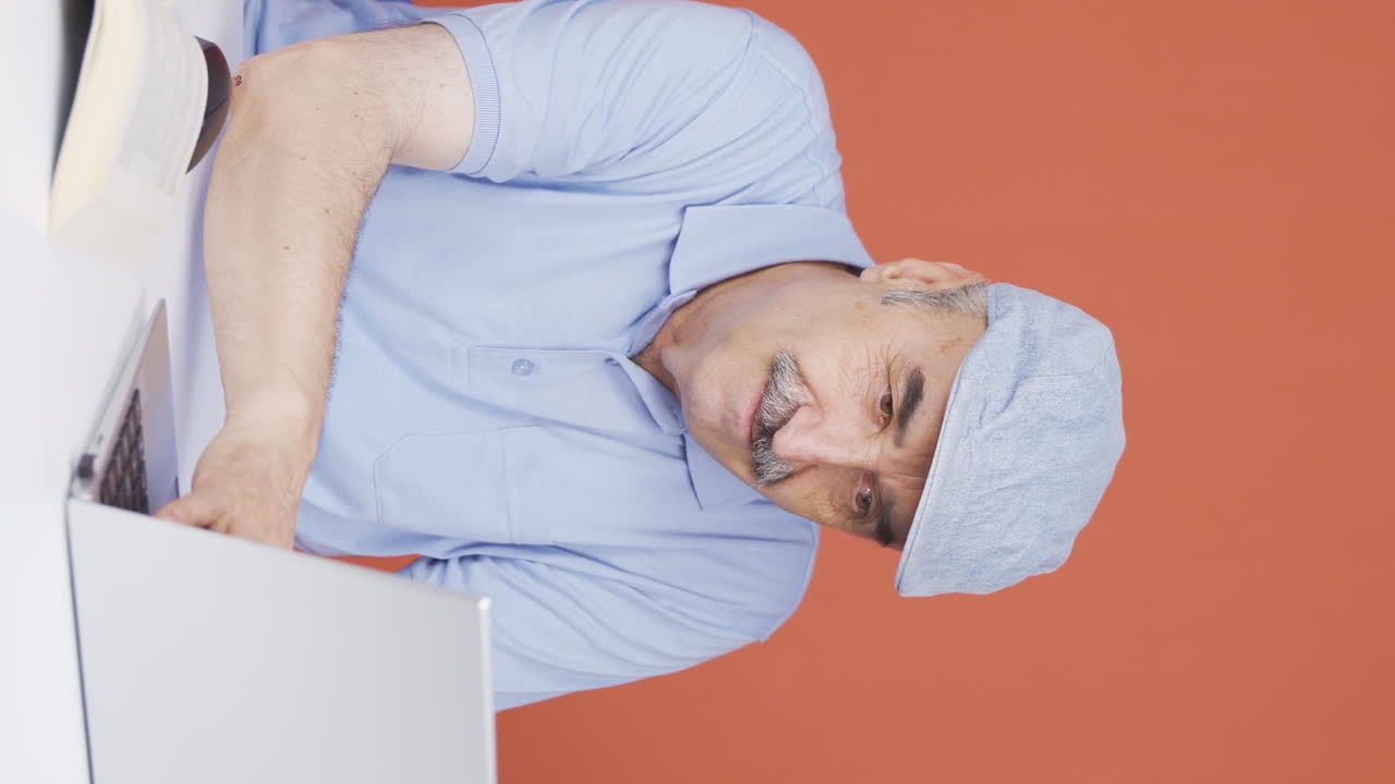 노인이 노트북으로 작업하는 수직 동영상입니다.