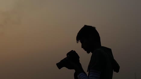 man with camera taking photographs at evening overcast sky, silhouette, static, profile