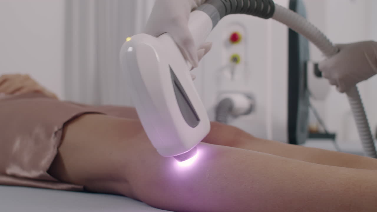 Beautician Performing Laser Epilation Treatment on Legs of Client