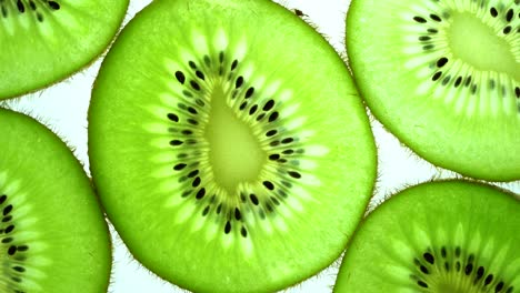vista superior girar una rebanada transparente de fruta de kiwi sobre un fondo blanco, cerrar el kiwi fresco cortado en rodajas sobre un fondo branco y girar lentamente.