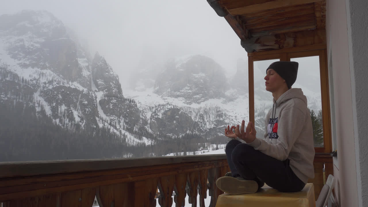 joven meditando mientras se sienta en la mesa con una montaña nevada en invierno en el fondo