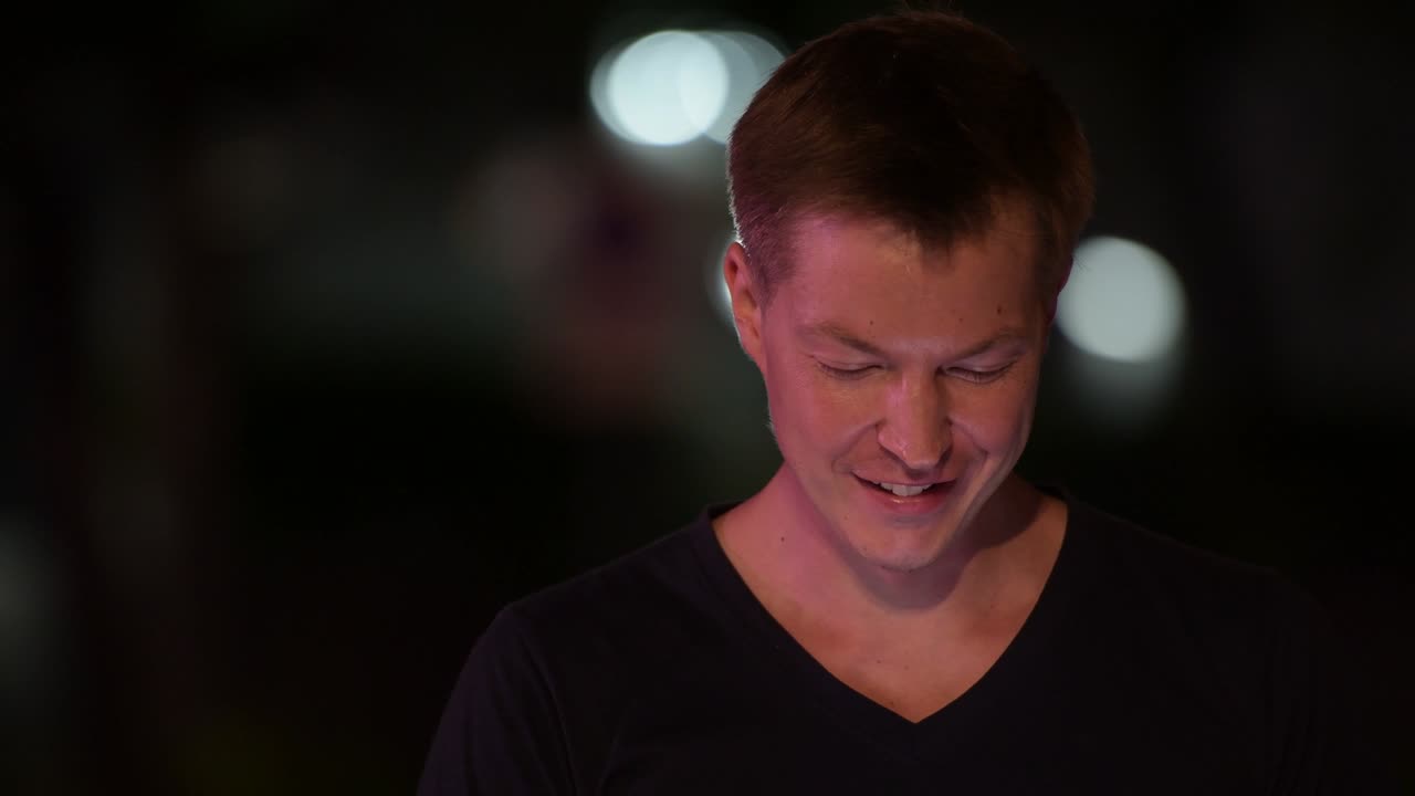 젊은 잘생긴 스칸디나비아 남자가 밤에 거리에서 전화를 사용합니다.