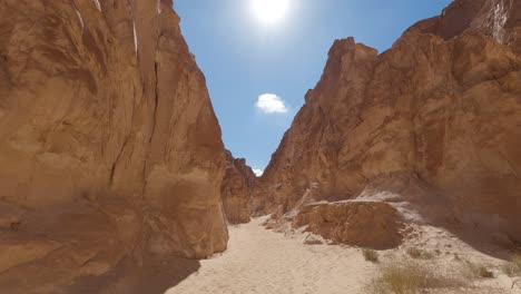 first person view of sandy colored canyon, south sinai, egypt, tilt shot to sunny blue sky