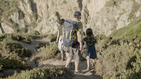 family of backpackers descending steep mountain slope