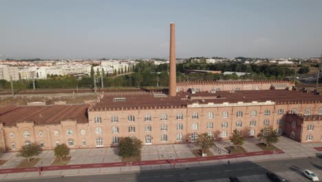 Antiguo-Edificio-De-Fábrica-Con-Chimenea-Alta-Y-Paisaje-Urbano-De-Aveiro-En-El-Horizonte,-Vista-Ascendente-De-Drones