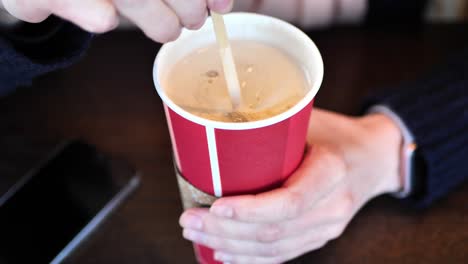 clip taken at coffee shop cafe of a caucasian women stirring a holiday coffee shop cup with hot coffee or tea in it