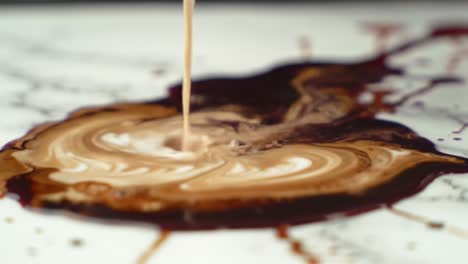 a captivating transformation: dark liquid swirls into a creamy marbled pattern on a marble surface, showcasing an intriguing blend of colors and textures