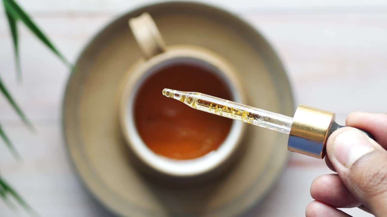 té relajante y gotero de aceite dorado