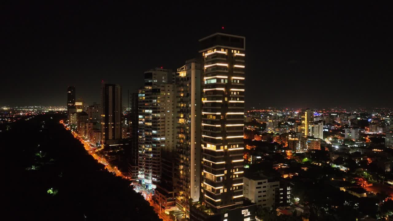 toma ascendente de drones de la ciudad iluminada de santo domingo por la noche con edificios de gran altura
