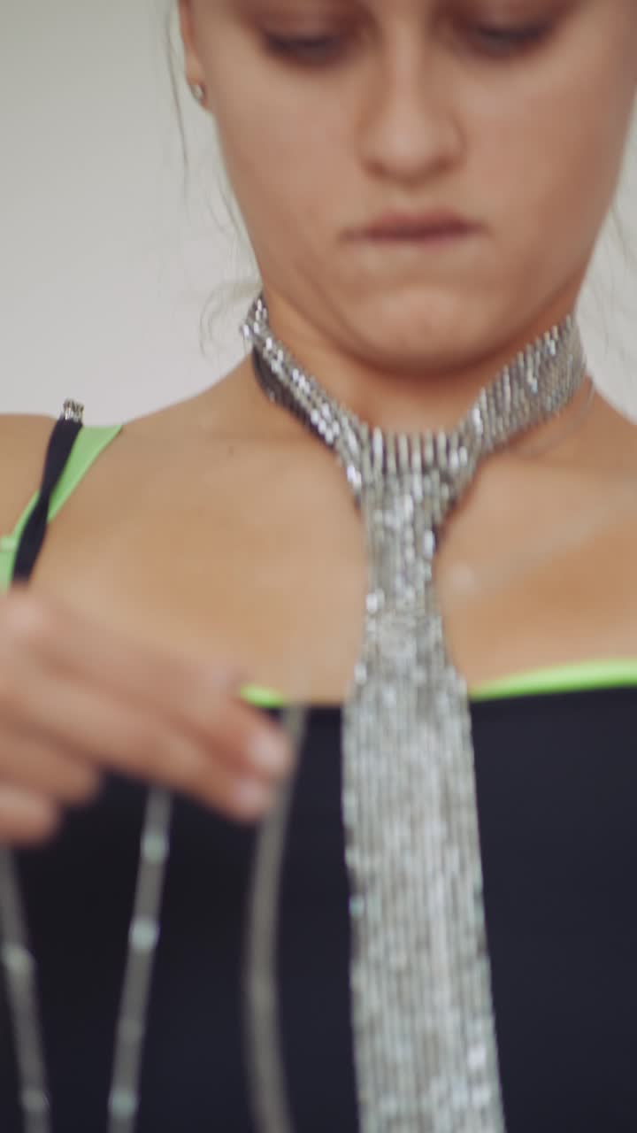 Woman's Hands Adjusting a Long Silver Chain Accessory