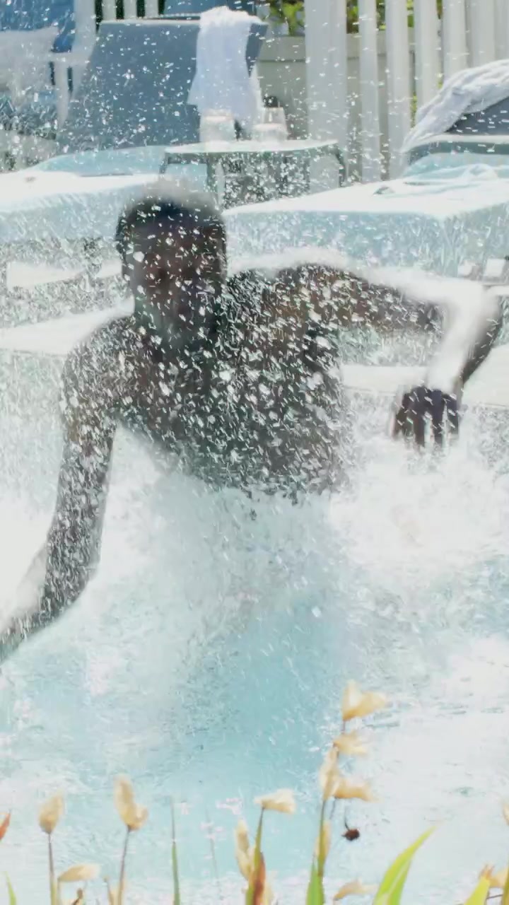 Video vertical: Hombre con bañador rosa corriendo y zambulléndose en una piscina soleada para divertirse.