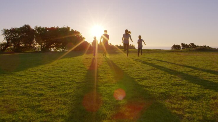 Young white family running towards moving camera in a park