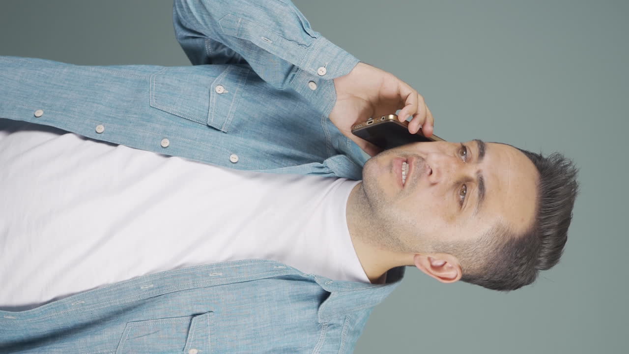 화난 남자가 전화로 이야기하는 수직 비디오.