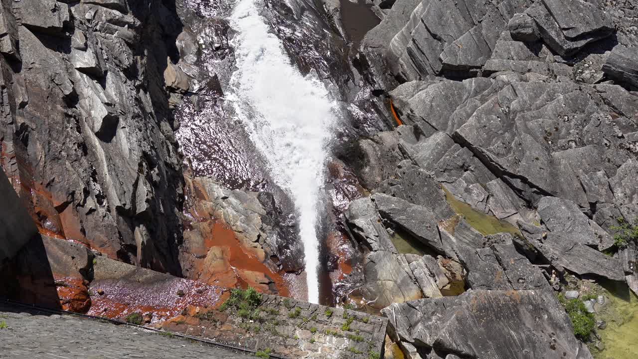 Low Level outlet pipe with stream of water from bottom of Storefossen dam in Norway - Ensuring continuous flow of water in the river for environmental needs - High angle looking down from dam