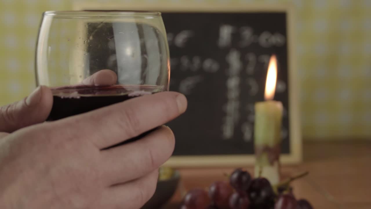 Pouring red wine into a glass in bar with candle close up shot