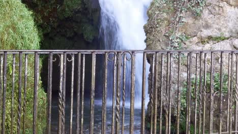metal guard railing with idyllic rural splashing waterfall flowing in background