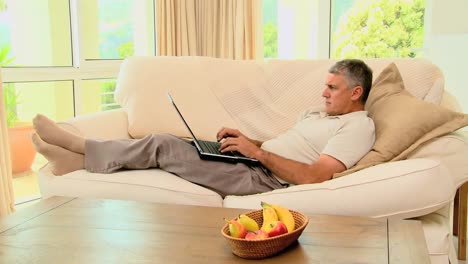 -Man-lying-on-sofa-while-working