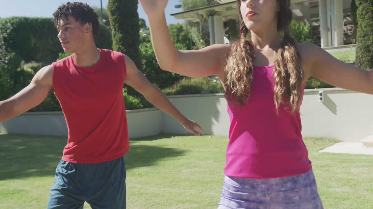 pareja biracial enfocada practicando yoga y haciendo poses en el jardín en un día soleado