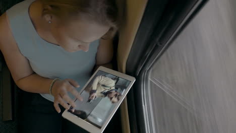 una joven con una tableta pc mirando fotos en el tren