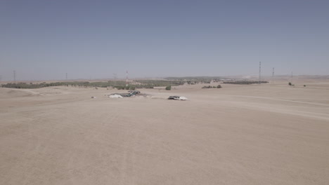 bedouin tents in an arid and remote area, on a dry sand field off the grid, near large power lines