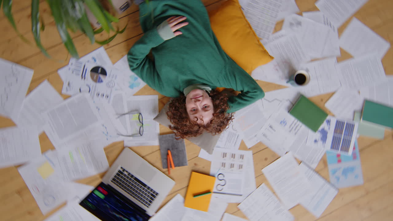 Happy Female Freelancer Lying among Papers at Home