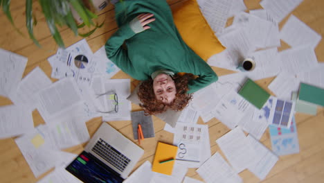 happy female freelancer lying among papers at home