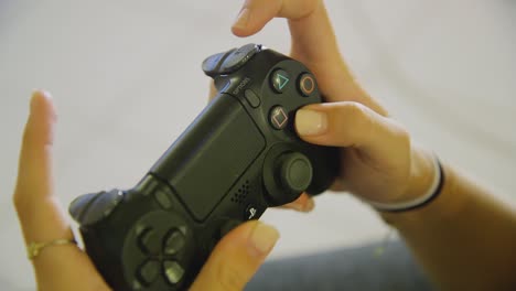 primer plano de las manos femeninas usando activamente el controlador dualshock ps4 negro para jugar dentro del interior de la casa