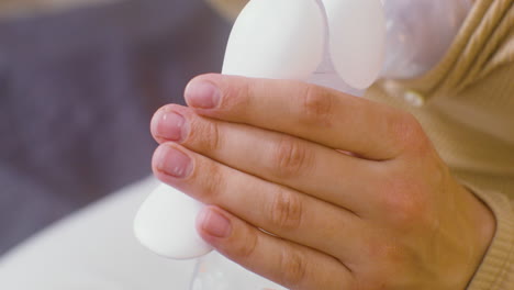 primer plano de manos femeninas usando un extractor de leche